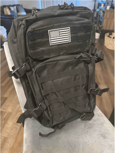 Black tactical backpack with American flag patch on a chair indoors