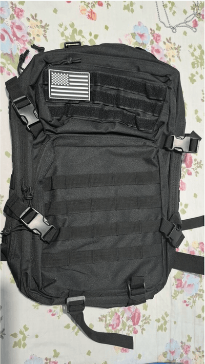 Black tactical backpack with American flag patch on a floral background