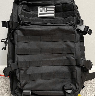 Black tactical backpack with American flag patch on a light gray background