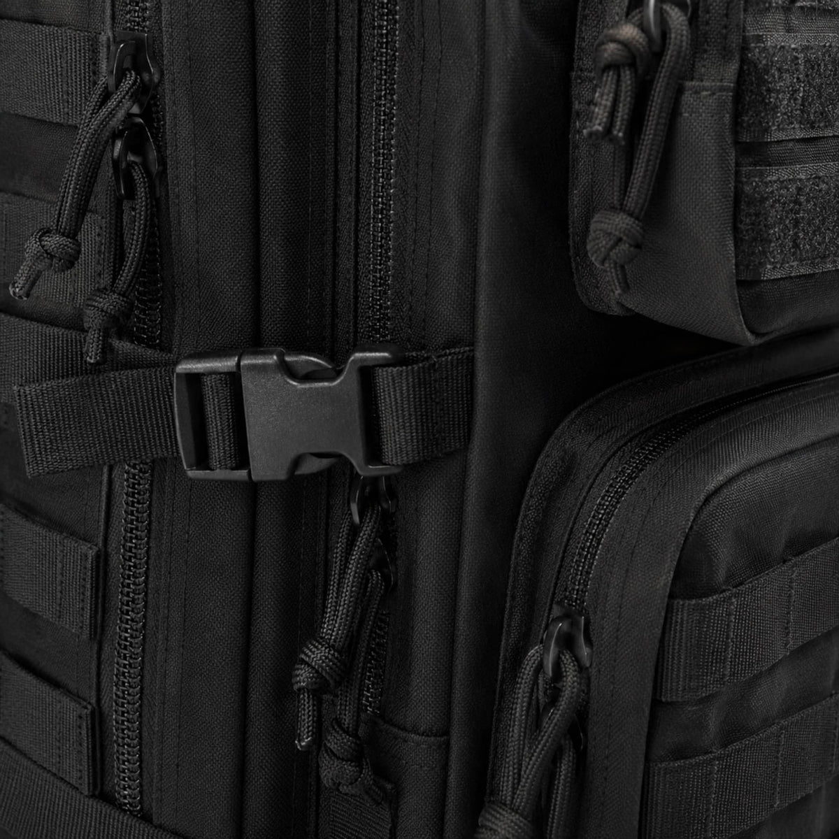 Close-up of subdued American flag patch and MOLLE webbing on front pocket of black tactical travel bag
