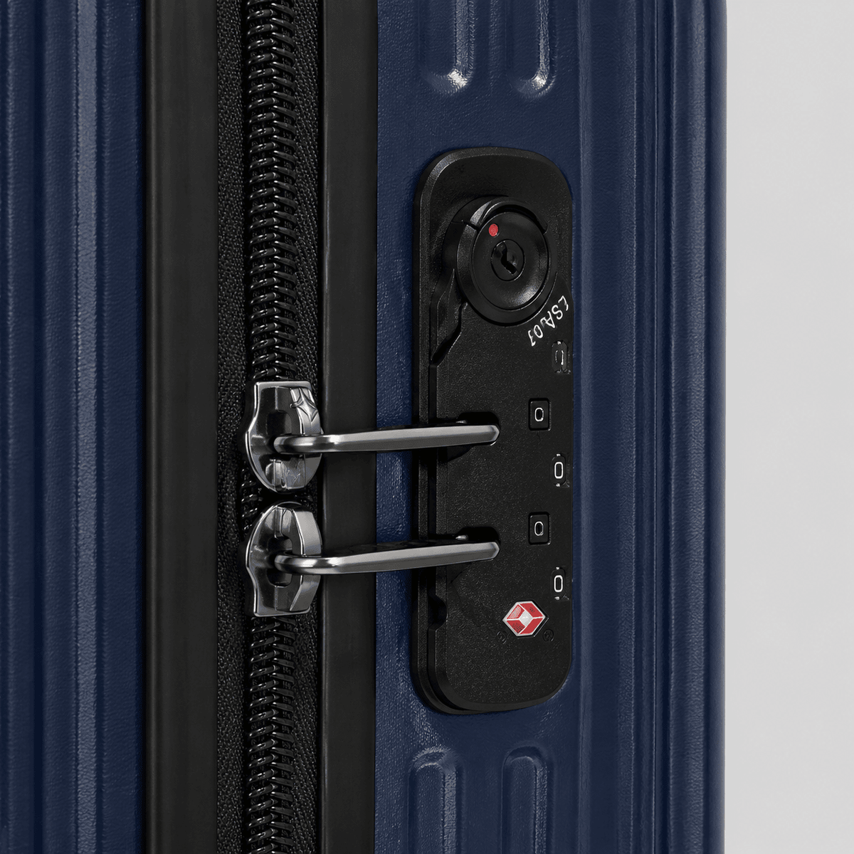 Close-up of TSA combination lock built into the side frame of a navy blue hardshell large carry on suitcase
