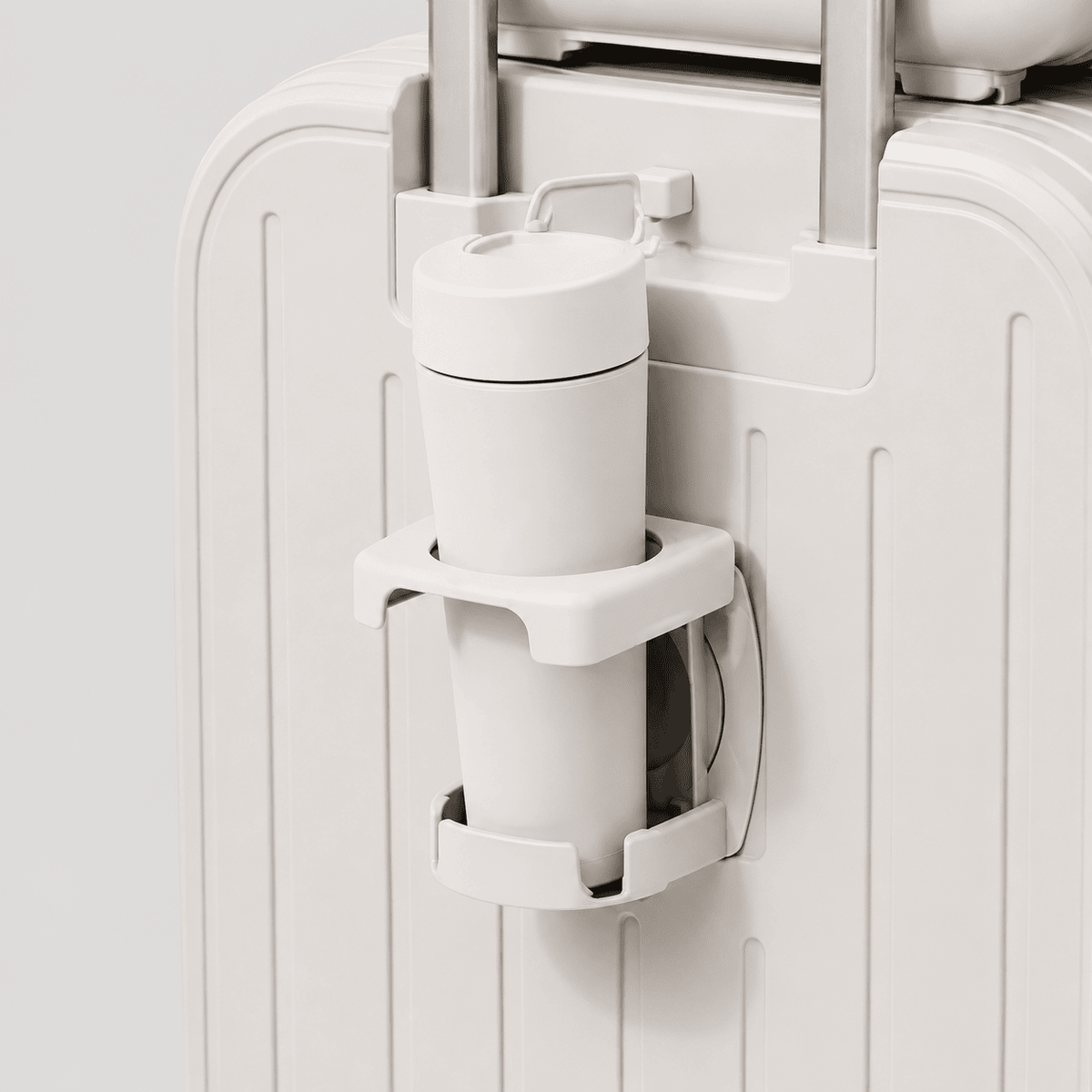 Close-up of built-in cup holder on the front of a cream white carry on luggage with white tumbler inserted
