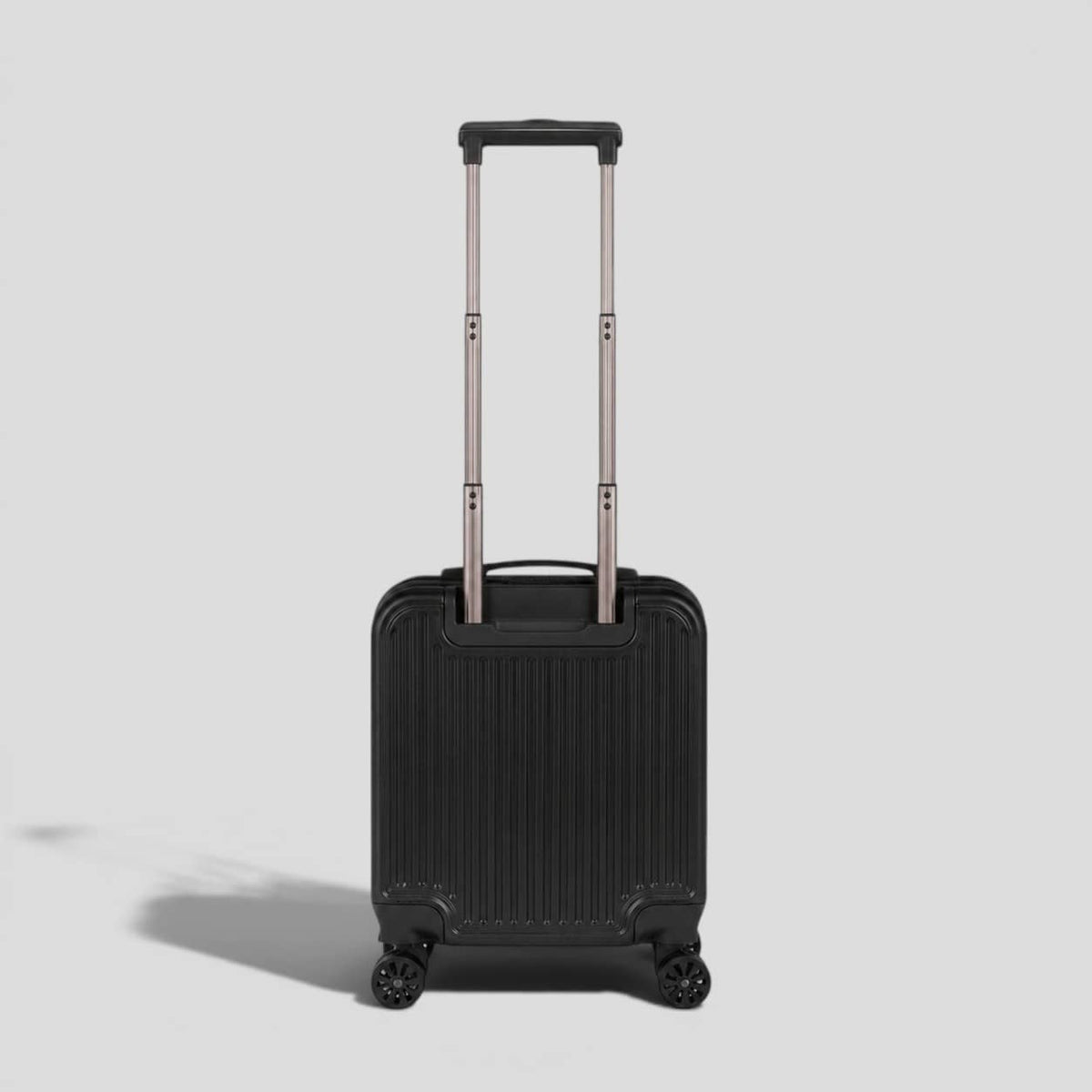 Back view. Black onyx hardshell small carry on luggage with extended telescoping handle, ribbed exterior, 360 spinner wheels, and front zip pocket